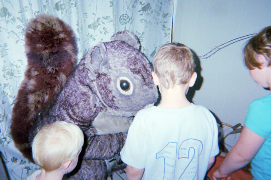 Photo from Sappyfest 2013 of three children looking at a squirrel mascost